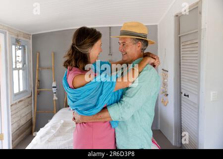 Vista laterale della coppia causiana senior che si abbraccia e si guarda mentre si è in piedi nella camera da letto Foto Stock