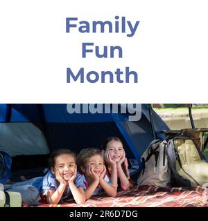Composto da testo del mese di divertimento per tutta la famiglia e fratelli caucasici sorridenti con le mani sul mento sdraiato in tenda Foto Stock