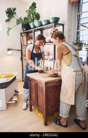 La migliore classe per un vasaio in erba. due giovani donne impastano l'argilla in uno studio di ceramica. Foto Stock