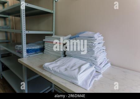 Biancheria impilata ordinatamente sugli scaffali. Ci sono lenzuola piegate, asciugamani, vestiti da lavare Foto Stock