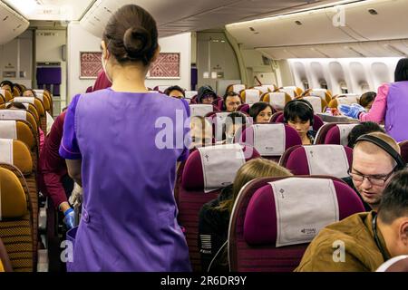 L'equipaggio di cabina della Thai Airways indossa un facemask che serve i passeggeri nella sezione Economy sul volo internazionale da Manila a Bangkok Foto Stock