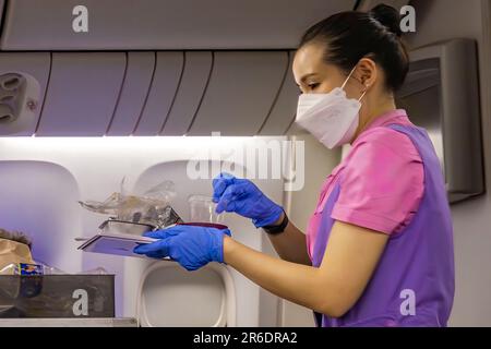 L'equipaggio di cabina della Thai Airways indossa un facemask che serve i passeggeri nella sezione Economy sul volo internazionale da Manila a Bangkok Foto Stock