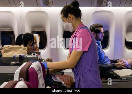 L'equipaggio di cabina della Thai Airways indossa un facemask che serve i passeggeri nella sezione Economy sul volo internazionale da Manila a Bangkok Foto Stock