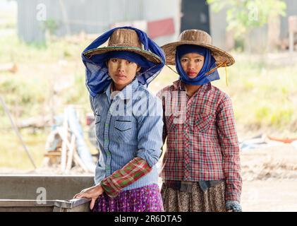 Due giovani lavoratrici in una fattoria di pesce al Delta di Irrawaddy in Myanmar. Profondità di campo bassa con solo la donna a sinistra in fuoco. Foto Stock