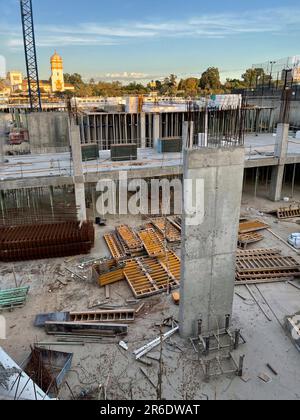 Un'alta struttura in cemento si erge adiacente ad un progetto di costruzione non finito, con una varietà di utensili e materiali da costruzione sparsi intorno a t Foto Stock