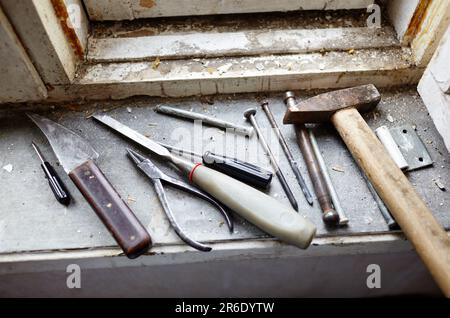 Riparazione del vecchio finestrino danneggiato o smontaggio prima di installare il nuovo primo piano. Riparazione di un telaio di una finestra, utilizzando strumenti per la ristrutturazione di vecchie finestre Foto Stock