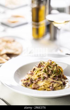 Piatti tipici italiani, spaghetti alla carbonara, impilati su un piatto dal tipico colore giallo e rosso. Foto Stock