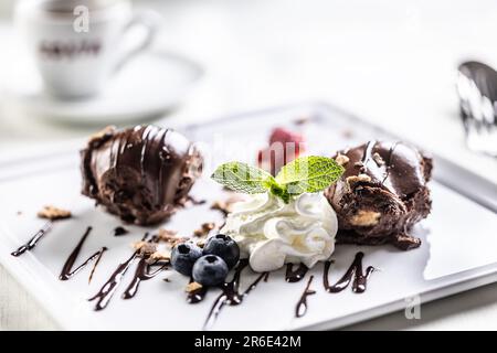 Dessert con palle di cioccolato dolce con panna montata, mirtilli e menta. Foto Stock