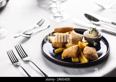 Pezzi di formaggio impanati fritti con patatine fritte e serviti con maionese. Menu per bambini in un ristorante elegante con pepite di pollo e fette di patate. Foto Stock