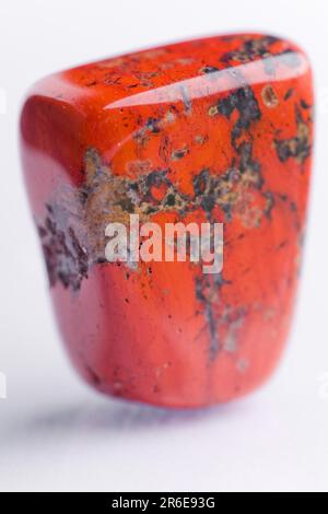 Pietra naturale rosso jasper brilla in bei colori su uno sfondo bianco Foto Stock