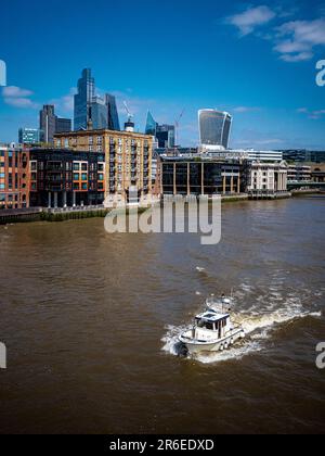 Fiume Tamigi City di Londra - una piccola barca naviga sul Tamigi attraverso il quartiere finanziario della città di Londra. Foto Stock