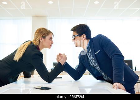 Concorrenti aziendali seri e sicuri che partecipano al wrestling ARM per dimostrare la leadership nella lotta onesta in carica Foto Stock