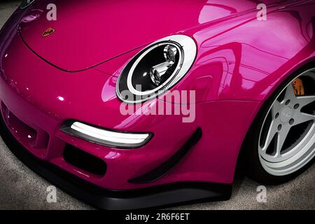 Un primo piano di una Porsche 911 rosa anteriore con un logo sul suo cappuccio Foto Stock