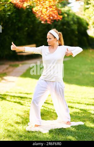 Bella donna sana praticare yoga nel parco estivo o giardino, arciere posa o Dhanurasana Foto Stock