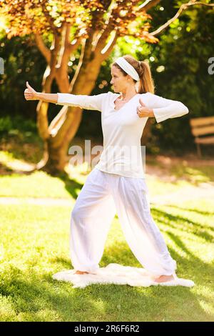 Bella donna sana praticare yoga nel parco estivo o giardino, arciere posa o Dhanurasana Foto Stock