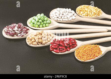 Una vita ferma di cucchiai di legno, ognuno riempito con una varietà di fagioli colorati e jelly beans Foto Stock