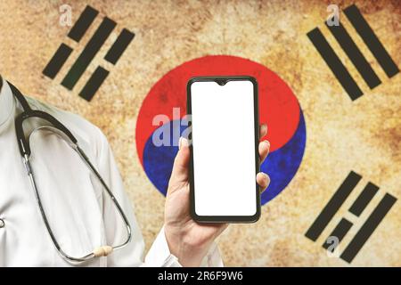 Una mano di una persona che tiene in mano un telefono cellulare con uno spazio copia sulla mappa della Corea del Sud Foto Stock