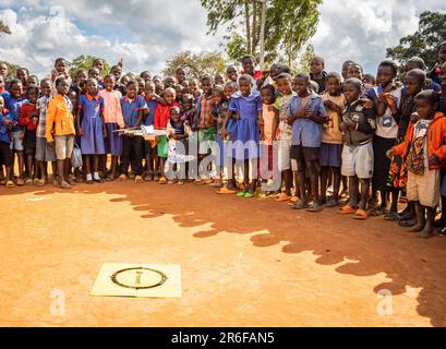 Gli scolari di una scuola malawia guardano mentre un UAV (drone) decolla dal loro terreno scolastico. Foto Stock