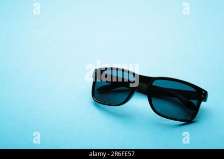 Eleganti occhiali da sole neri su sfondo blu con spazio copia. Vista dall'alto Foto Stock