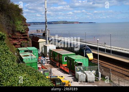 Un treno che passa attraverso la stazione di Dawlish durante i lavori di costruzione per costruire una nuova piattaforma e ponte pedonale nel 2023. Foto Stock