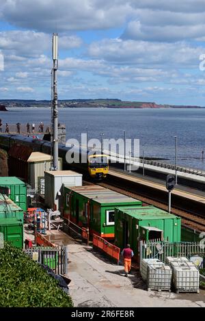 Un treno che passa attraverso la stazione di Dawlish durante i lavori di costruzione per costruire una nuova piattaforma e ponte pedonale nel 2023. Foto Stock