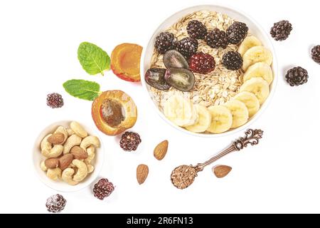 Una variopinta composizione di frutta secca assortita, frutta fresca e spezie su un piatto bianco Foto Stock