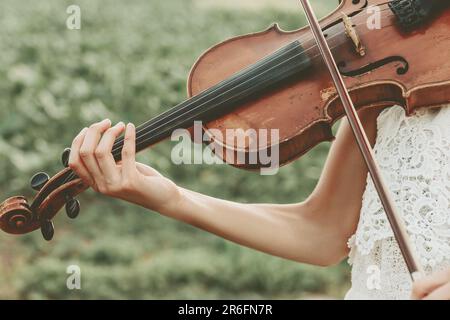 Una musicista femminile in un abito stupefacente che esegue un pezzo classico su un violino Foto Stock