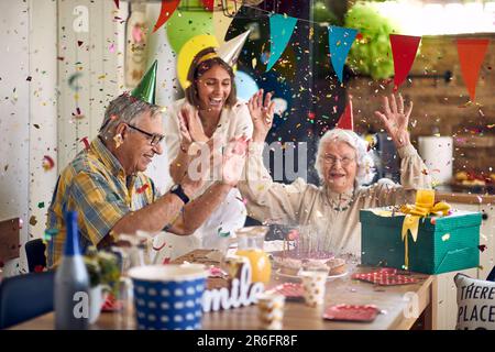 Famiglia felice di coppia anziana e figlia che festeggia il compleanno di una donna anziana, celebrando il suo compleanno insieme, insieme nella cucina di casa da dinn Foto Stock