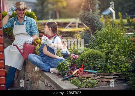 Padre e figlia si sono impegnati in una profonda conversazione e compagnia nel loro giardino. L'ambiente sereno fornisce un ambiente tranquillo come condividono le specifiche Foto Stock
