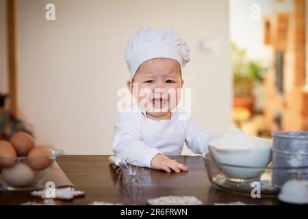 9-mese-vecchio bambino asiatico vuole cuocere biscotti di zenzero di Natale, pianti e richieste Foto Stock