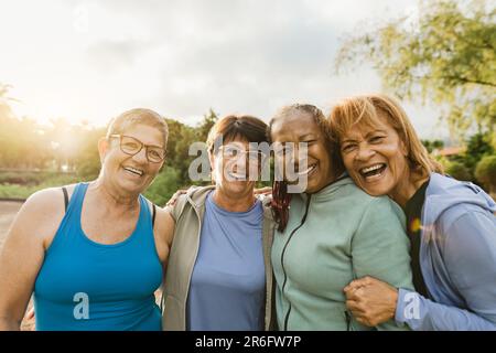 Felici amici multirazziali femmina che si divertono sorridendo davanti alla macchina fotografica dopo una sessione di allenamento al parco Foto Stock