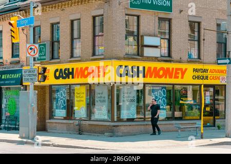 Toronto, Canada - 4 giugno 2023: Un uomo che cammina su un marciapiede lungo un edificio commerciale. Payday Advance Cheques Cash viene visualizzato in modo preminente sul Foto Stock