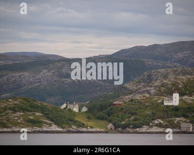 Una casa colonica rustica situata sulla costa norvegese, con un esterno in pietra intatto, circondata da un tranquillo paesaggio rurale Foto Stock