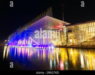 Fontana danzante in luci di Natale che si riflette in acqua Foto Stock