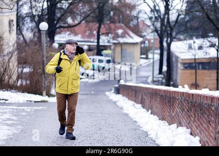 un uomo cammina lungo una bella strada della città e parla al telefono Foto Stock