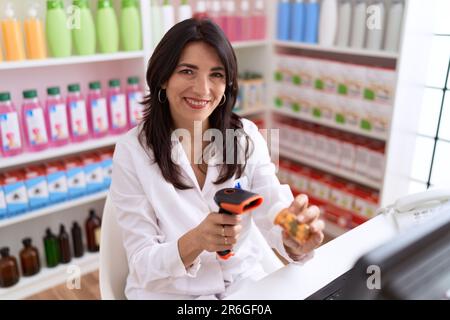 Età media donna ispanica farmacista pillole scansione flacone in farmacia Foto Stock
