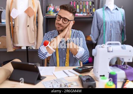 Uomo ispanico con Beard dresssaker designer che lavora presso atelier dormire stanco sognando e posando con le mani insieme, mentre sorridendo con gli occhi chiusi. Foto Stock
