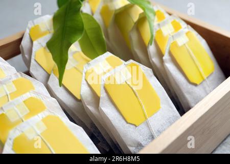 Scatola di legno con sacchetti di carta da tè sul tavolo, primo piano Foto Stock