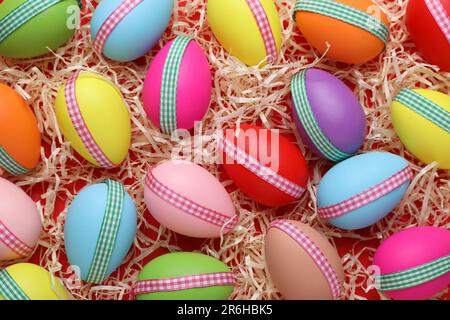 Uova di Pasqua decorate festivamente in filler di carta su sfondo rosso, giacitura piatta Foto Stock