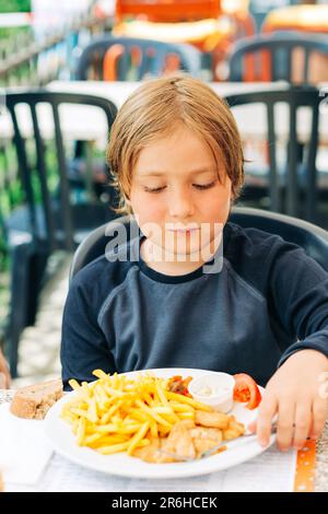 I bambini mangiano patatine fritte e pepite di pollo nel ristorante all'aperto Foto Stock