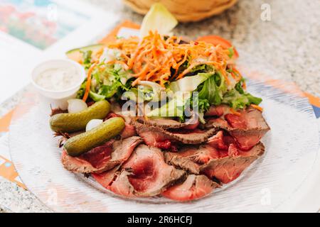 Roastbeef con carote fresche e insalata verde servita nel ristorante Foto Stock