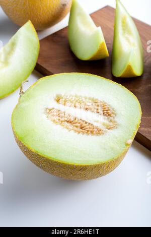 Metà melone e pezzi di melone a fette su sfondo bianco. Foto Stock