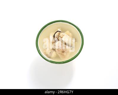 Un recipiente bianco con un recipiente caldo per la cottura a vapore di zuppa di pollo composto da verdure e pezzi di pollo Foto Stock