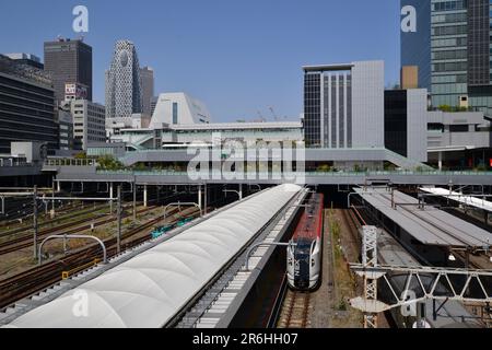 La vista frontale dei binari ferroviari che entrano nella massiccia ed enorme stazione ferroviaria di Shinjuku di Tokyo e' circondata da alti edifici di uffici e dai treni della Japan Rail Foto Stock