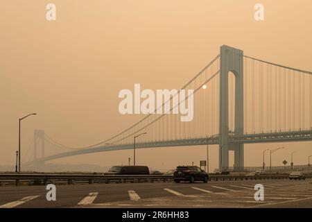 Vista sul ponte Verrazzano-Narrows e sulla città di New York sorpresi dal fumo di arancio intenso dei fuochi selvatici del Québec Foto Stock