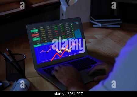 Uomo che analizza la situazione sul mercato di borsa via laptop, primo piano. Dati e grafico sullo schermo Foto Stock