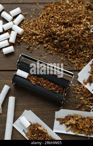 Composizione piana con rullo e tabacco su tavola di legno. Fare le sigarette arrotolate a mano Foto Stock