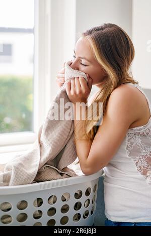 Donna, servizio di pulizia e biancheria pulita odore o pulizia vestiti, tessuto o coperta con fragranza e felice routine casa. Persona, biancheria fresca e. Foto Stock