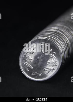 foto ravvicinata di una moneta indiana in argento lucido da una o 1 rupia disposta in fila dritta isolata su sfondo nero Foto Stock