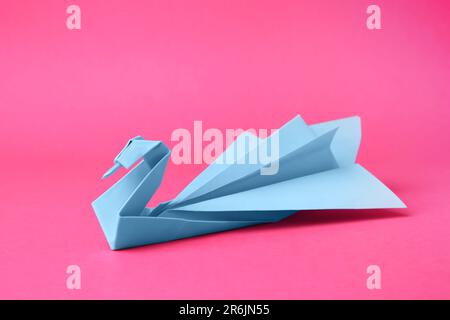 Carta blu chiaro cigno su sfondo rosa. Origami arte Foto Stock